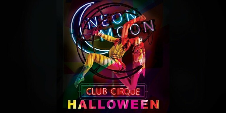 An aerial dancer balances on a neon moon