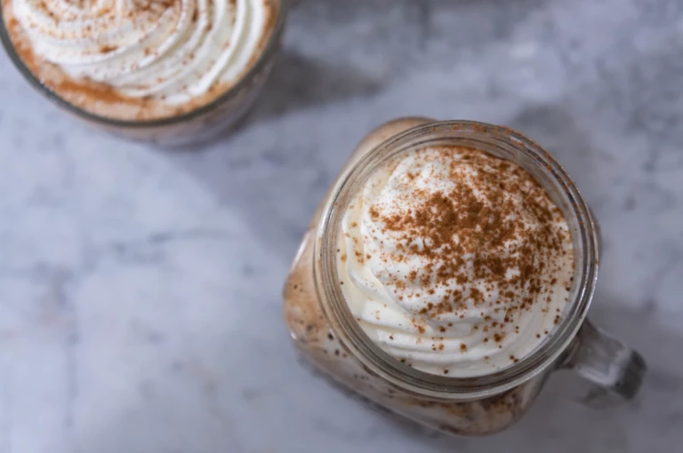 A mug of hot chocolate with swirled cream and sprinkles